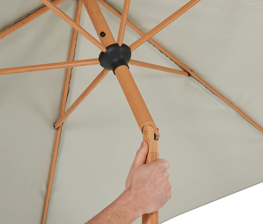 Eine Hand hält einen grauen Leco Marktschirm in Holzoptik inklusive Abdeckhaube.