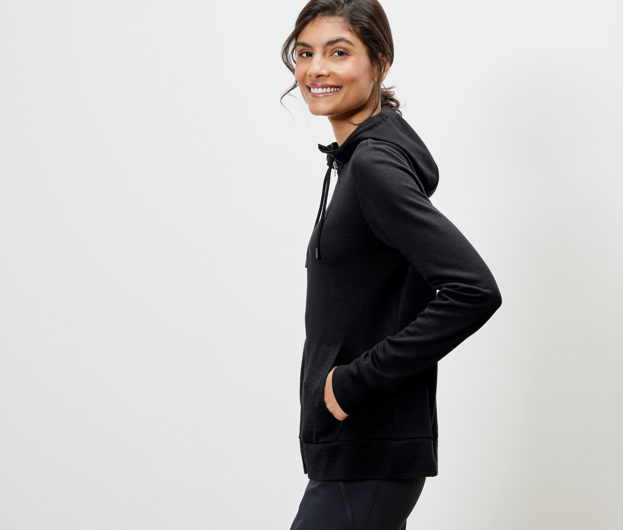 Frau posiert in schwarzer Kapuzenjacke mit RWS-zertifizierter Wolle.