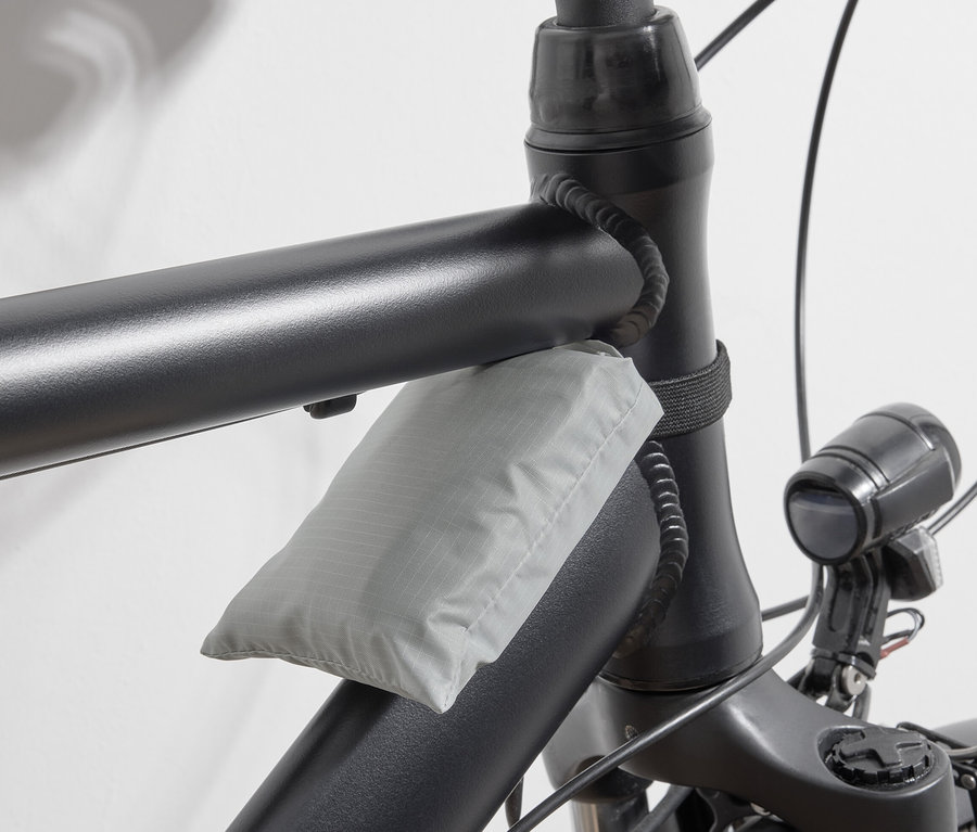 Graue Fahrrad-Einkaufstasche am Fahrradrahmen befestigt.