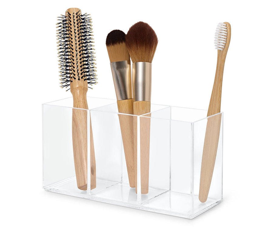 Haarbürste, zwei Make-up-Pinsel und eine Zahnbürste in einem transparenten Acryl-Organizer.