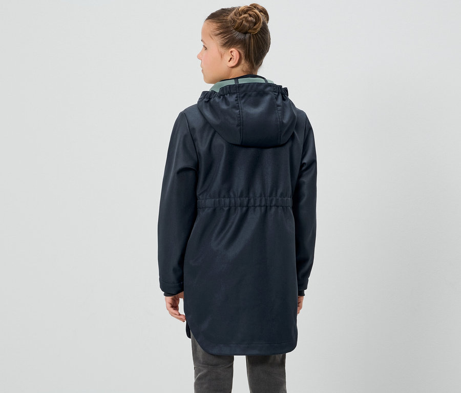 Mädchen steht mit dem Rücken zur Kamera und trägt eine Kinder-Softshellmantel.