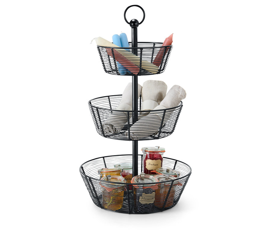 Ein dreistöckiger, schwarzer Drahtkorb-Etagenständer enthält Kerzen, Waschlappen und Einmachgläser.