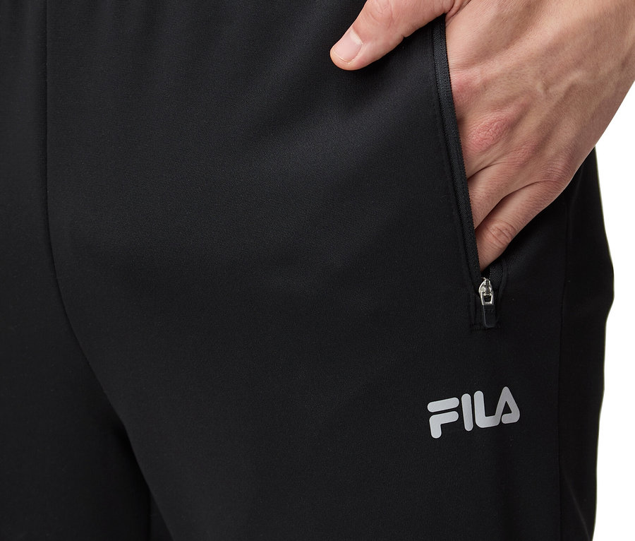 Mann steckt Hand in die Tasche einer schwarzen FILA Trainingshose.