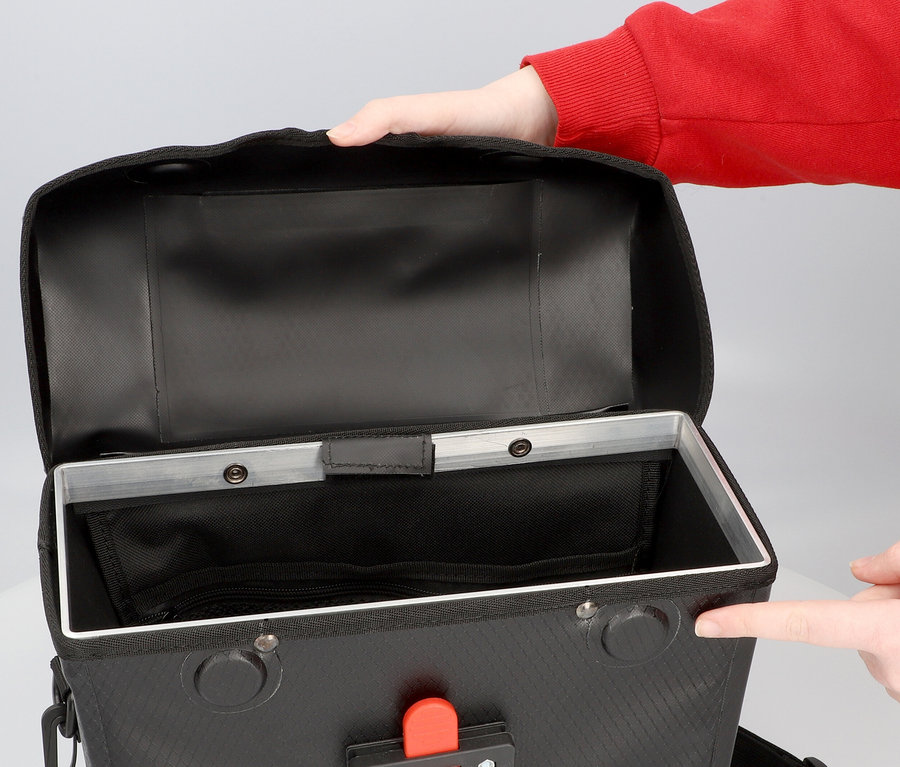 Person öffnet eine schwarze FISCHER Lenkertasche PLUS+ Terra.