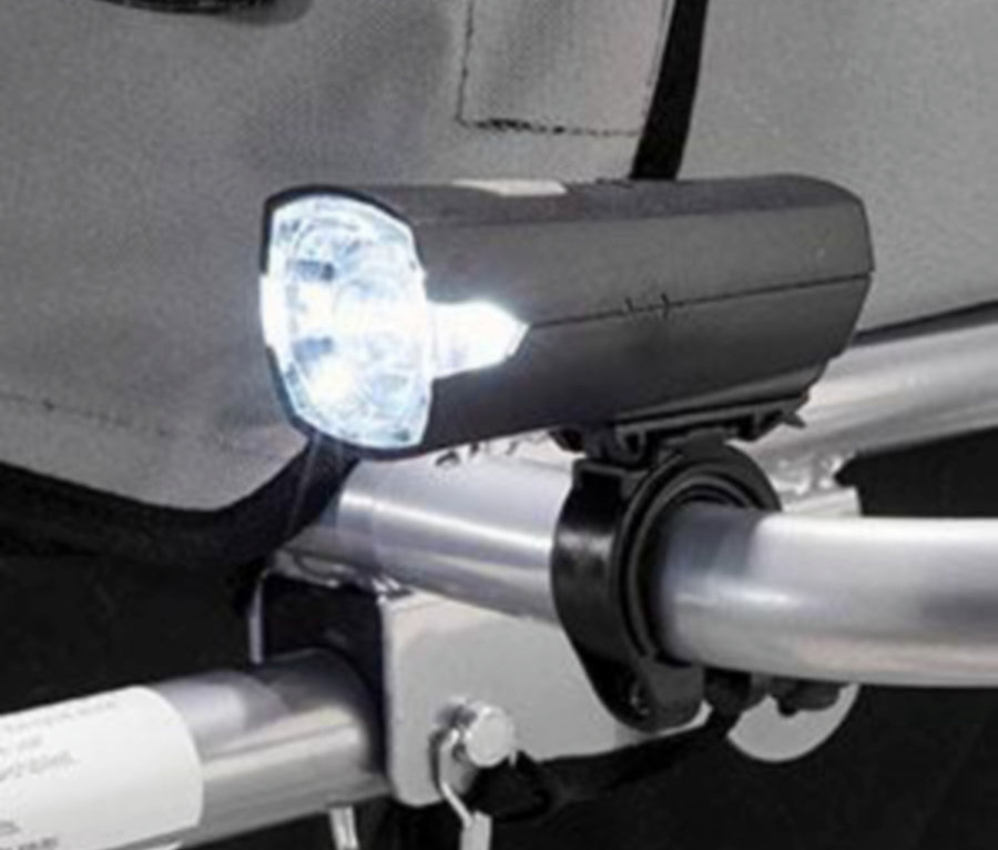 Nahaufnahme einer Fahrradlampe, die an einem silbernen Lenker befestigt ist und hell leuchtet.