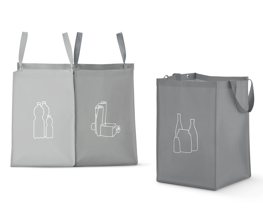Drei graue Recycling-Taschen mit weißen Symbolen für Plastikflaschen, Papier und Glas.