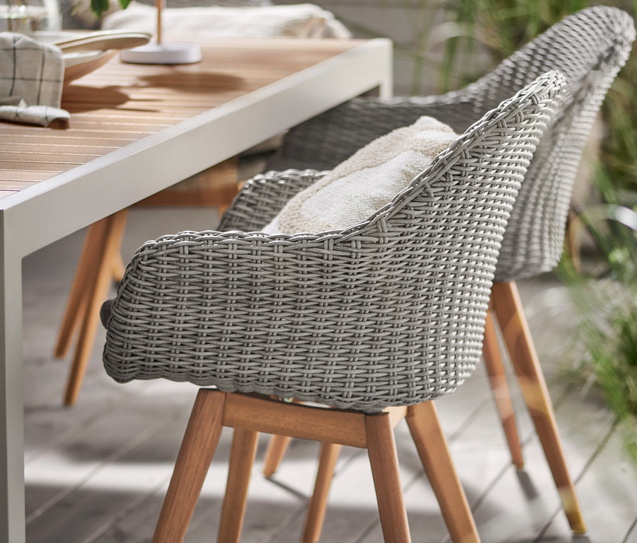 Detailansicht eines Liska Ausziehtischs, Polyrattan Stuhls und einer LED-Akku-Tischleuchte in Holzoptik.