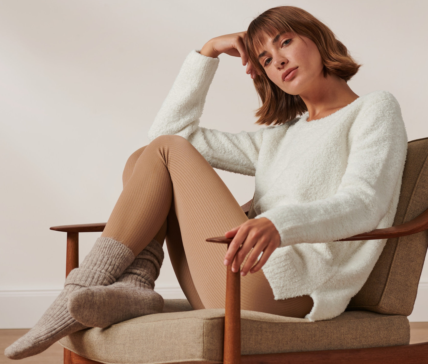 Frau sitzt im Sessel und trägt einen Kuschel-Sweater.