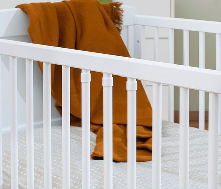 Detailansicht eines weißen Kinderbetts mit einer orangefarbenen Decke und einer gemusterten Unterlage. 3-teiliges Pinolino Set »Viktoria« breit