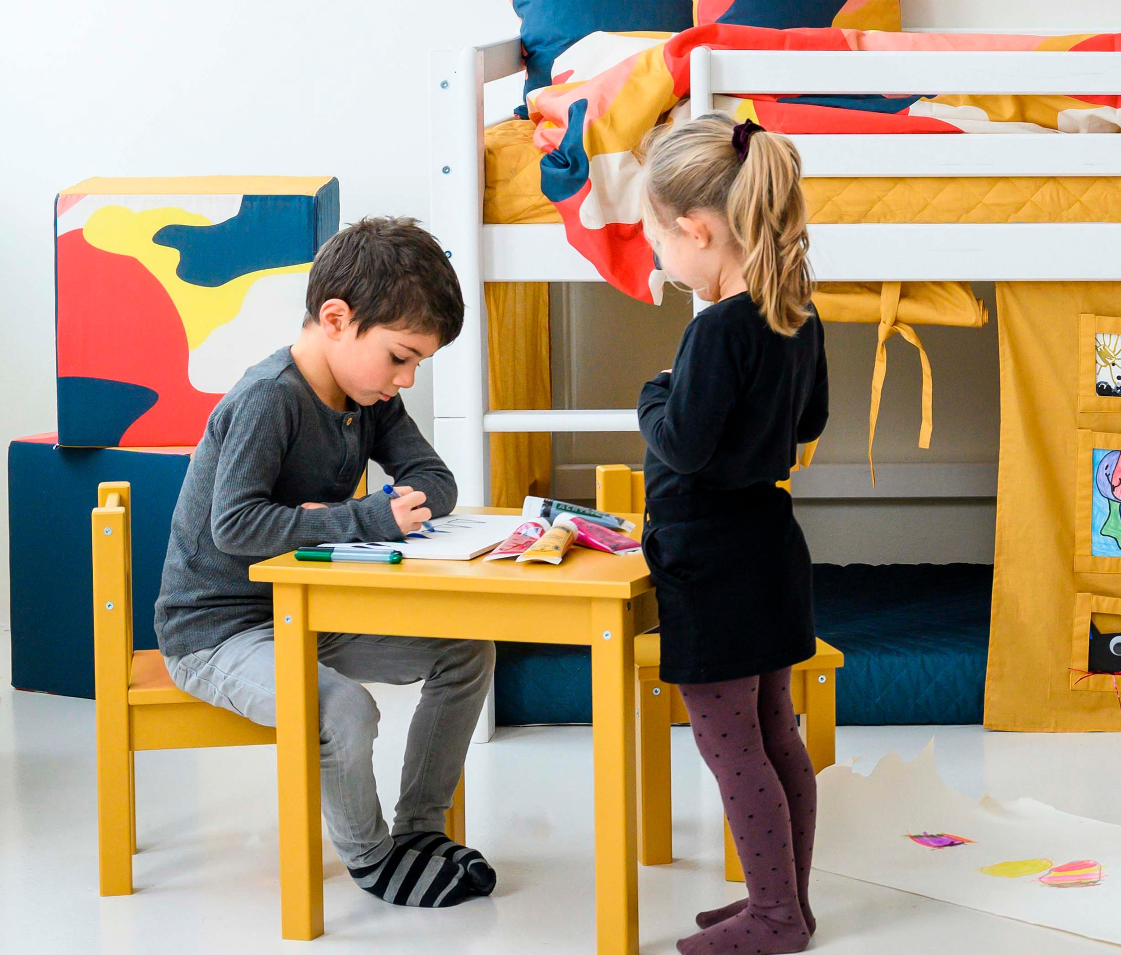 Junge malt am gelben Tisch. Daneben steht ein Mädchen. Im Hintergrund ist ein Hochbett zu sehen. Hoppekids Tisch-und-Stuhl-Set »Mads«, ockergelb.