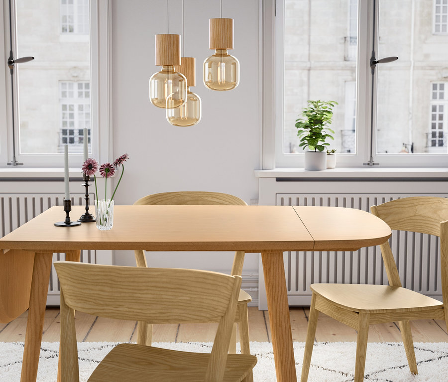 Ein Esstisch aus Holz mit drei Holzstühlen und einer Hängeleuchte aus Holz.