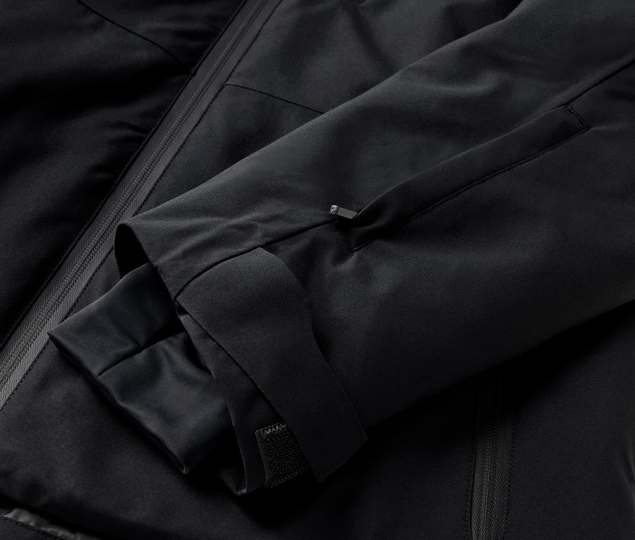 Detailaufnahme einer schwarzen Jacke mit Ärmel und Reißverschlusstasche.
