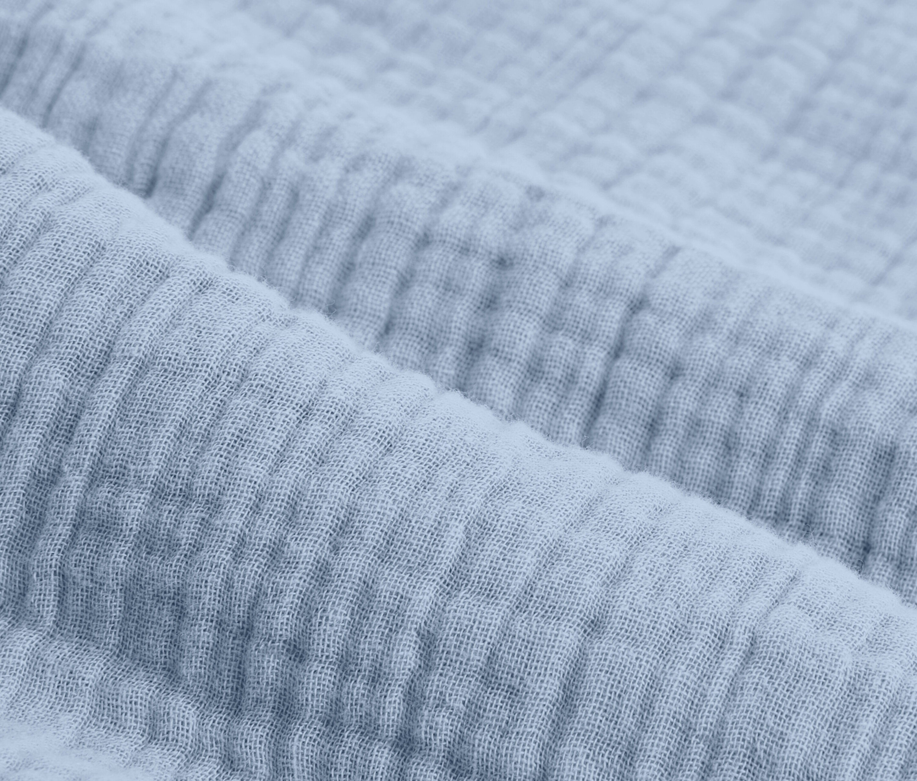 Nahaufnahme von hellblauer Musselin-Bettwäsche in Normalgröße.