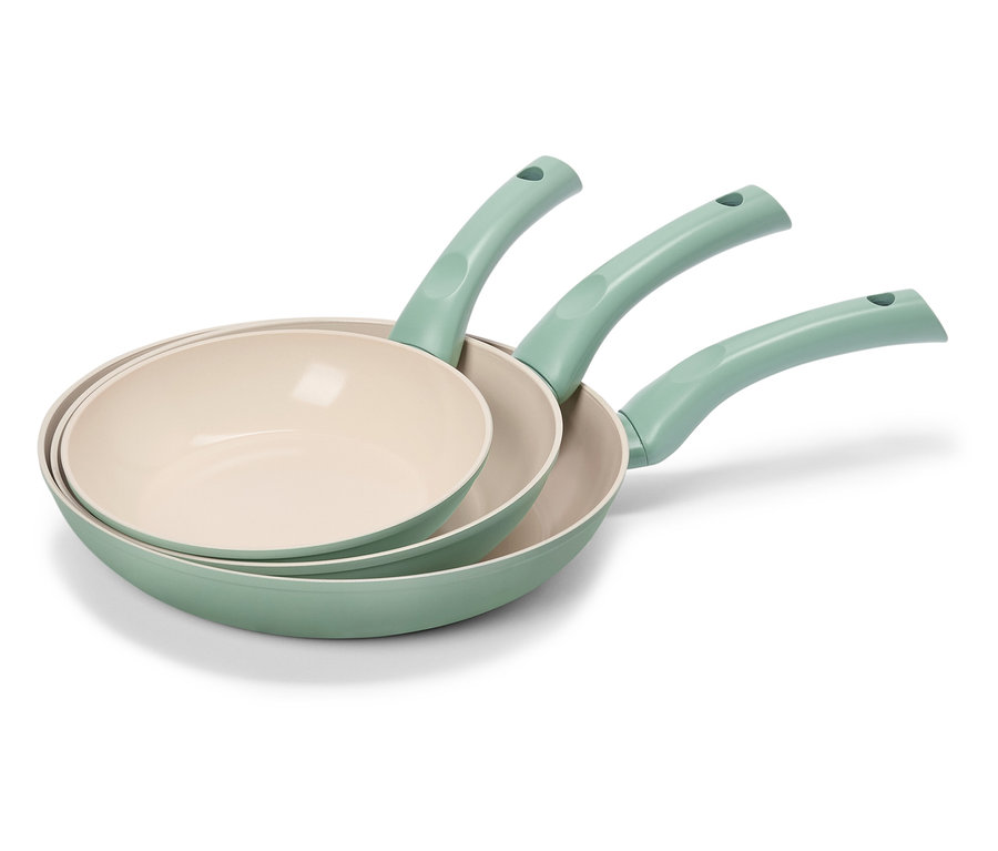 Drei grüne Bratpfannen mit cremefarbenen Innenflächen sind gestapelt.