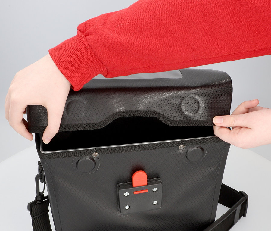 Person öffnet eine schwarze FISCHER Lenkertasche PLUS+ Terra.