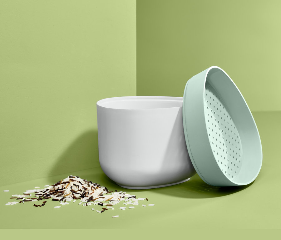 Weißer Mikrowellen-Reiskocher mit Reishaufen und grünem Deckel.