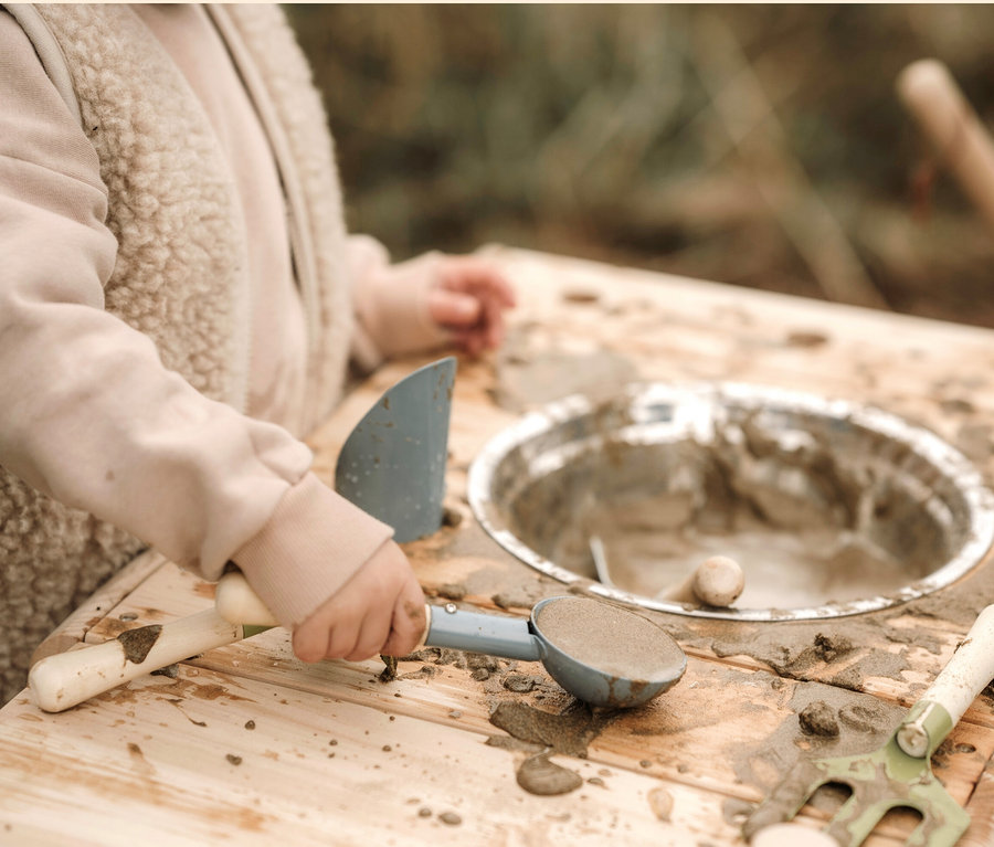 Kind spielt mit small foot Matschküche kompakt, benutzt blauen Löffel und Metallschüssel.