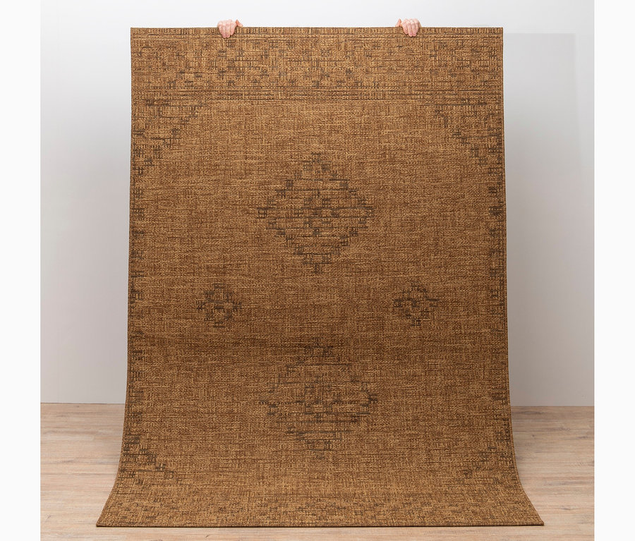 Person hält Teppich »Roy« in Braun mit Antik-Muster hoch.