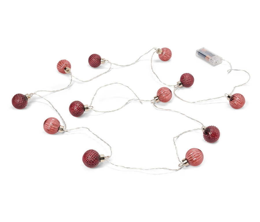Eine Lichterkette mit roten Kugeln und Batterien liegt auf einem weißen Hintergrund.