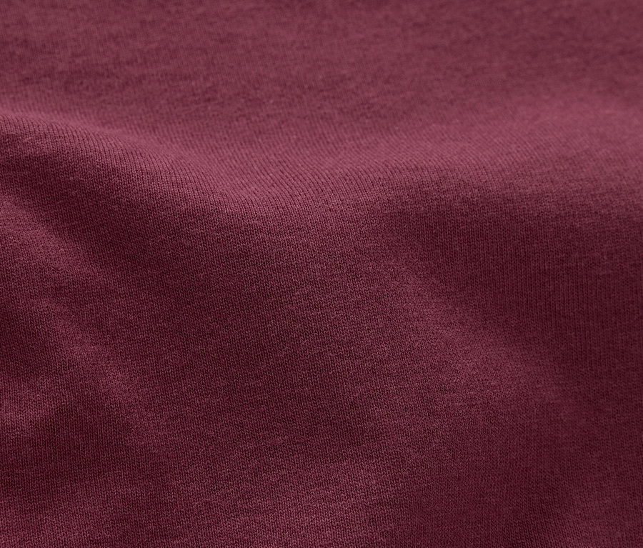 Nahaufnahme eines strukturierten, weinroten Stoffes.