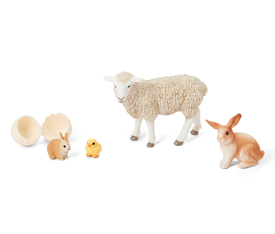 Ein geöffnetes Ei neben dem Schleich® Set »Ostertiere«, das ein Lamm, ein Kaninchen und ein Küken enthält.