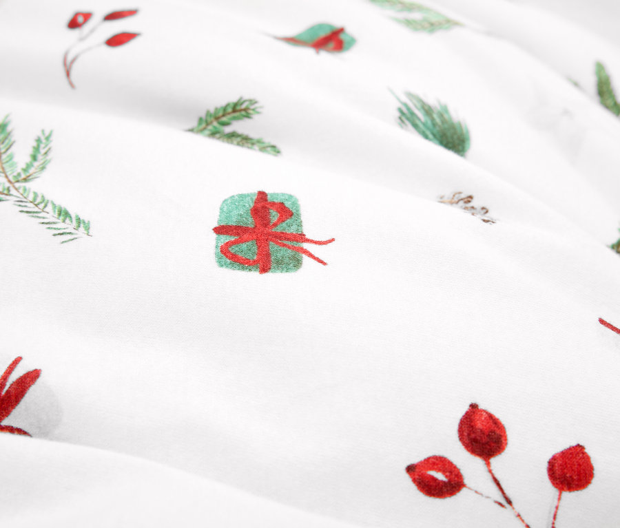 Detailaufnahme eines Stoffes mit Weihnachtsmotiven, grüne Zweige und rote Beeren.