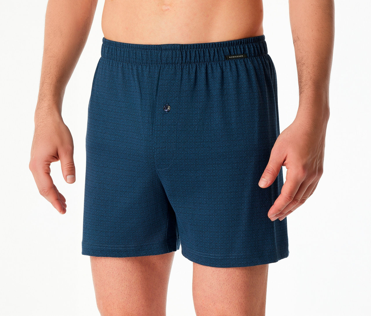 Mann trägt blaue 2 SCHIESSER Boxershorts mit Knopf und Gummibund vor weißem Hintergrund.