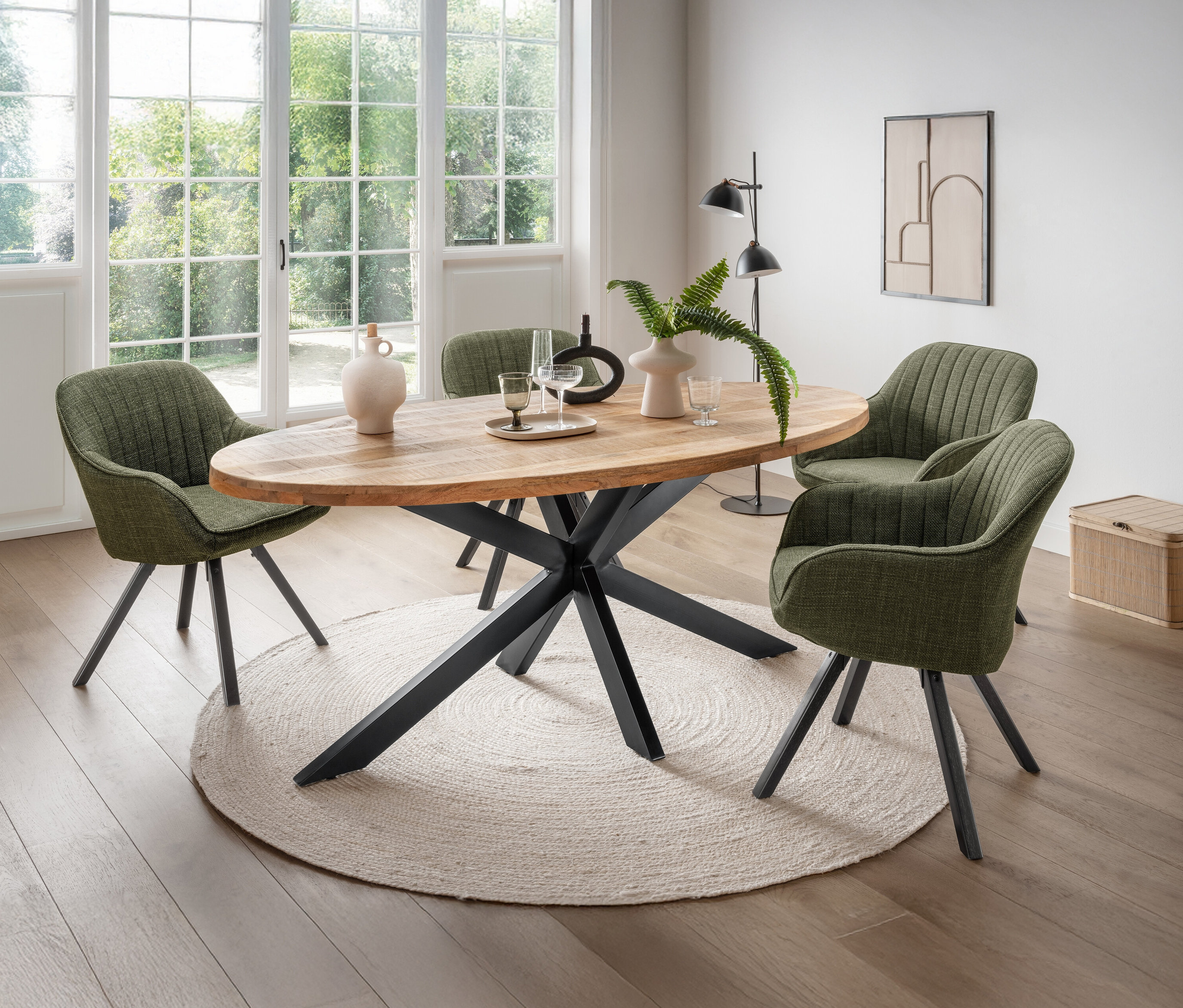 Esstisch mit vier grünen Stühlen, zwei Vasen, Gläsern und einem kleinen Tablett auf einem runden Teppich.