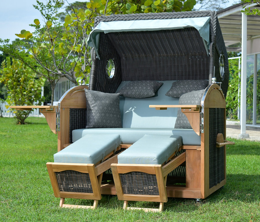 deVries Teak-Strandkorb, 2-Sitzer aus Teakholz steht auf einer Wiese.