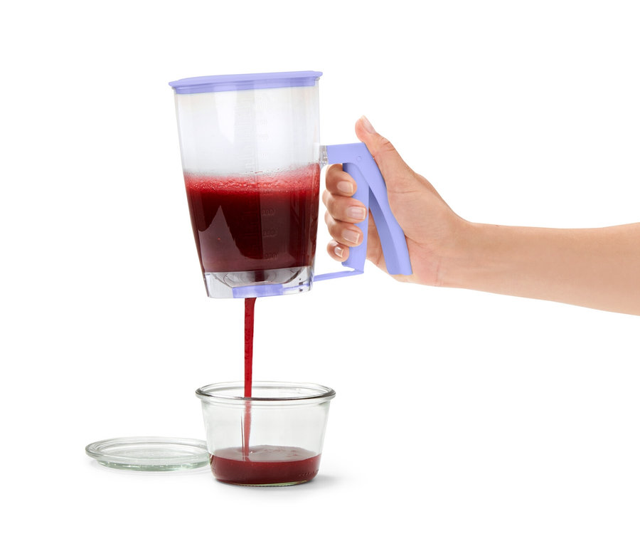 Frau giesst Teig aus einem Teigportionierer in ein Glas.