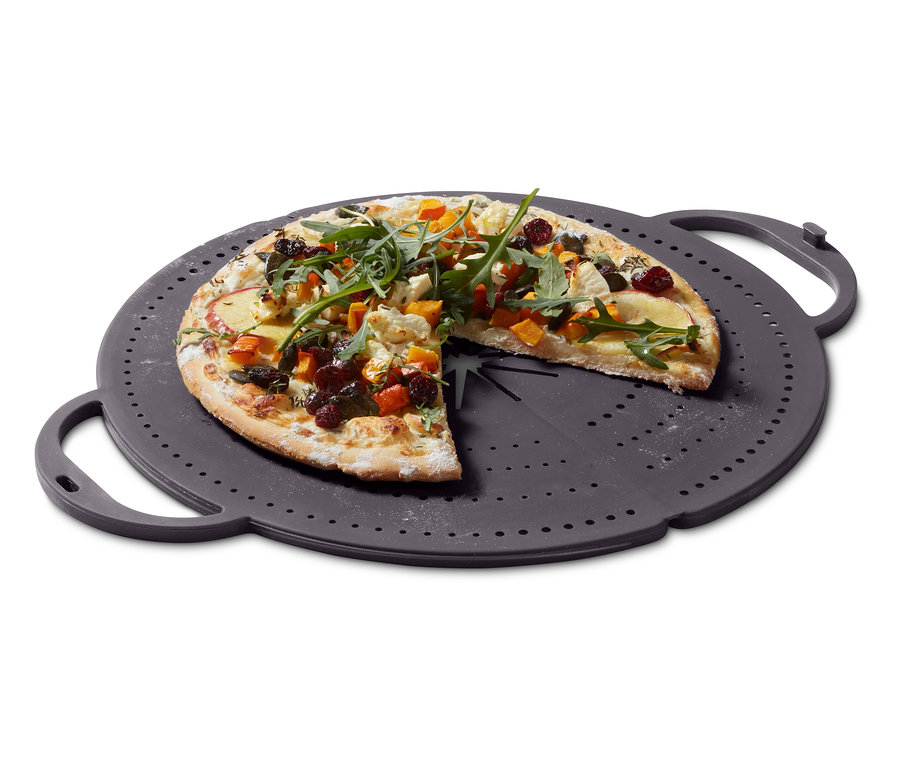 Pizza mit Herbstgemüse auf einem grauen, gelochten Tablett.