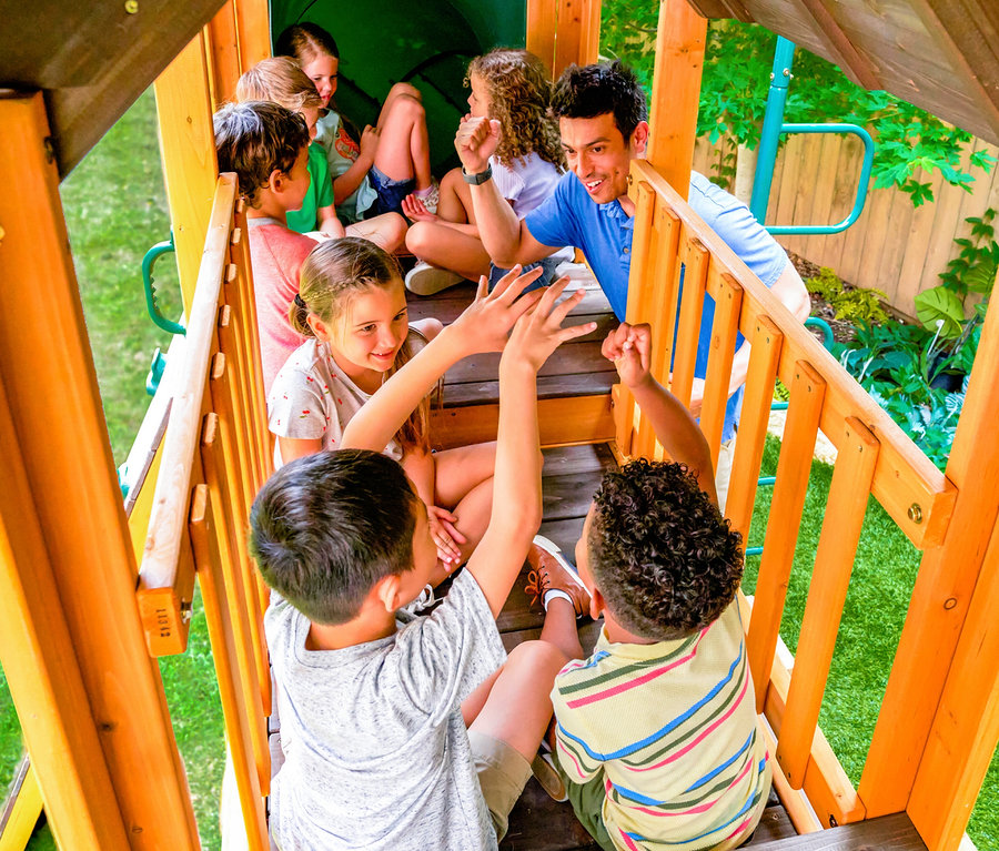 Mehrere Kinder und ein Mann sitzen auf einem »Bolzo« Spielturm und spielen.