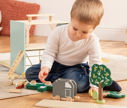 Ein Junge spielt mit dem Pinolino Spielwelt »Reiterhof Lise« Holzspielzeug.