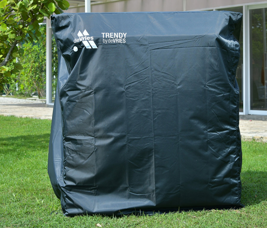 Ein abgedeckter deVries Teak-Strandkorb, 2-Sitzer steht auf einer Rasenfläche.