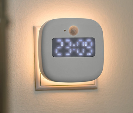 Ein Steckdosen-LED-Nachtlicht mit Uhr ist in eine Steckdose gesteckt.