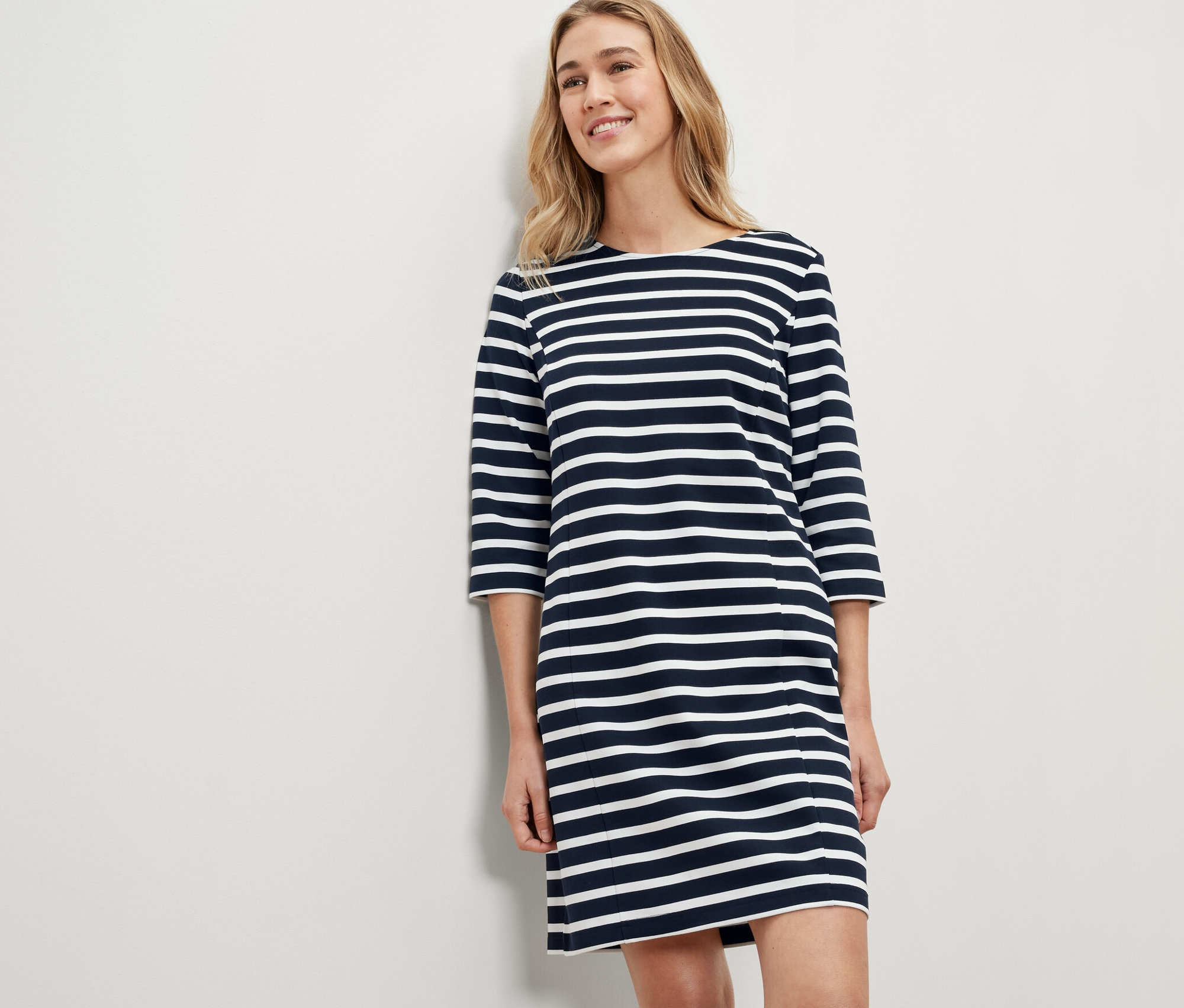 Blonde Frau trägt ein gestreiftes Sweatkleid.