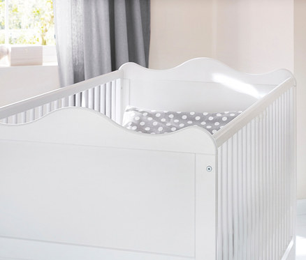 Detailansicht des weißen Kinderbetts mit einer grauen Decke mit weißen Punkten im Inneren.