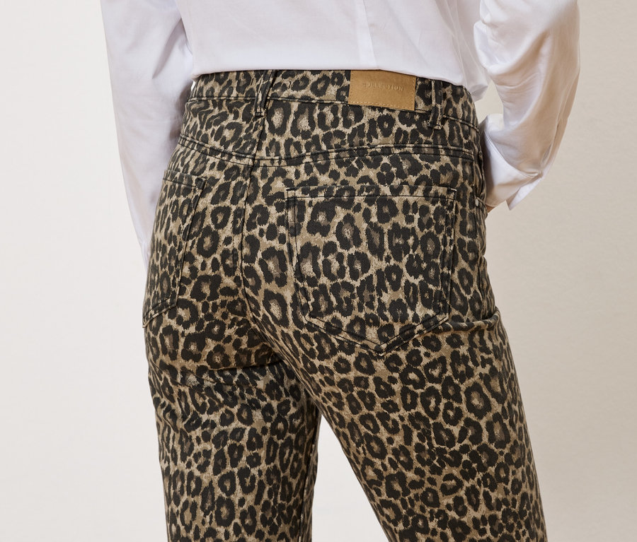 Rückansicht einer Person, die eine Hose mit Leopardenmuster und ein weißes Hemd trägt.