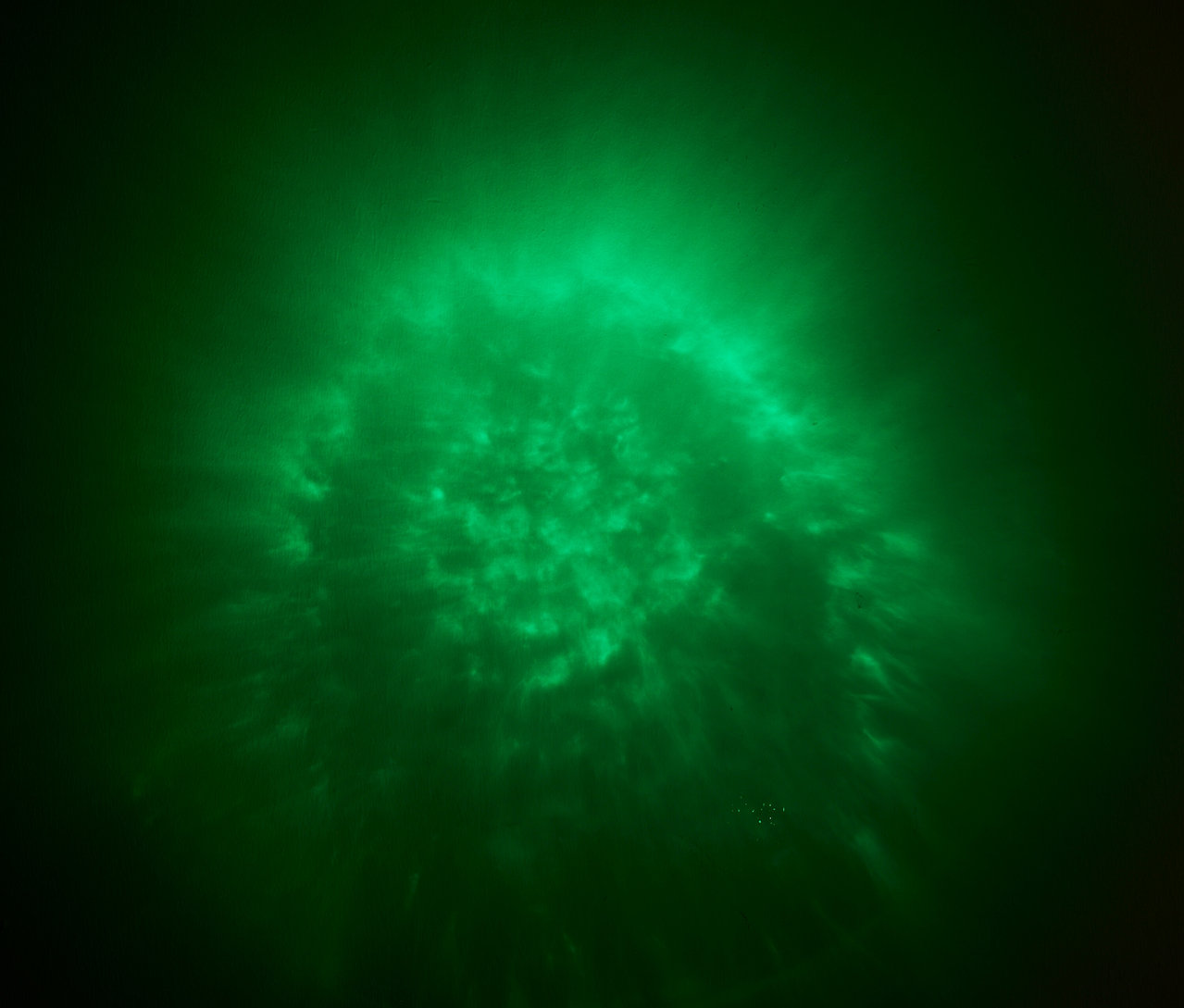 Grünes Licht mit einem diffusen Muster auf dunklem Hintergrund.