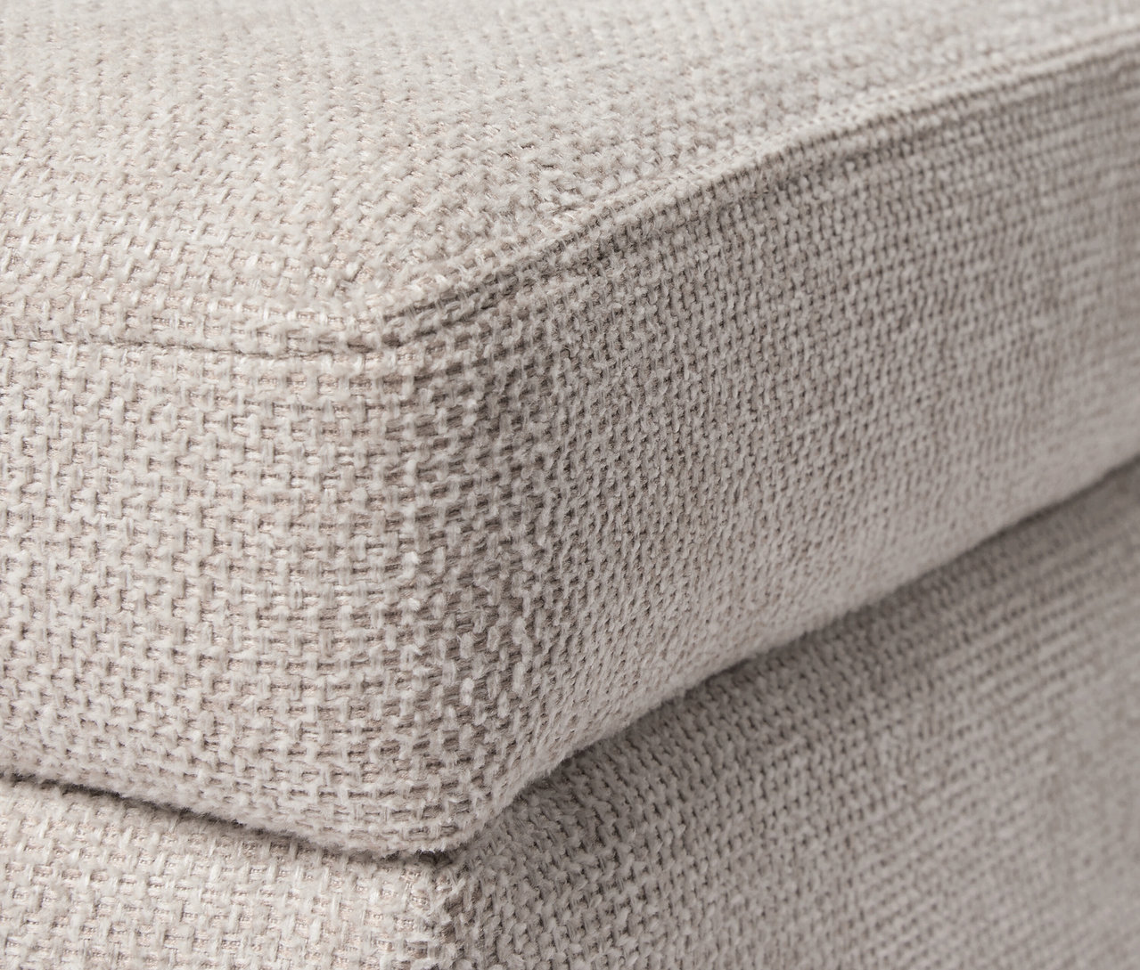 Detailaufnahme eines beigen Poufs. Fokus liegt auf der Textur des Poufs mit Rollen und Tablett.