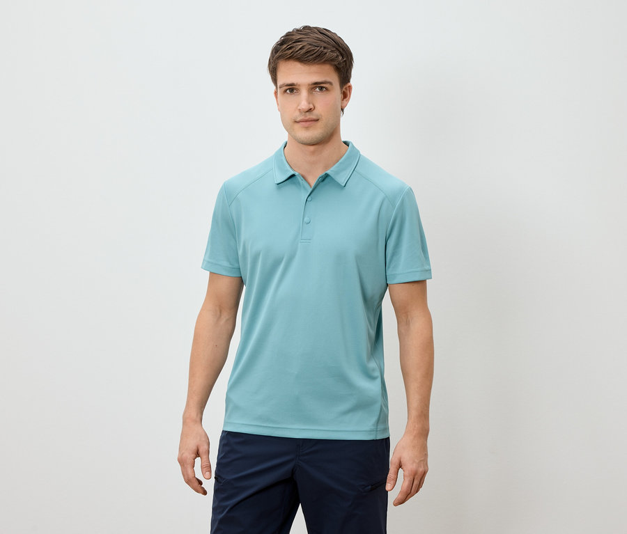 Mann steht vor hellem Hintergrund und trägt ein hellblaues Poloshirt und marineblaue Shorts.