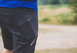 Nahaufnahme einer schwarzen Sportshorts mit den Umrissen eines Smartphones in der Reißverschlusstasche.
