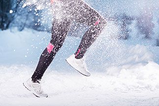 Eine Frau joggt im Schnee und trägt eine wärmende Sporthose.