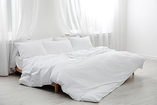 Die richtige Größe zum Wohlfühlen: Helles Schlafzimmer mit einem Doppelbett auf dem eine große Bettdecke liegt.