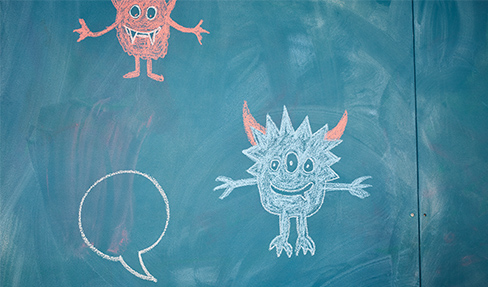 Kleine Monster mit Kreide an eine Tafel gezeichnet