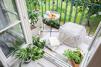 Platzwunder: Ein kleiner Balkon mit einem Sitzsack und Grünpflanzen auf dem ein kleiner, runder Gartentisch steht.