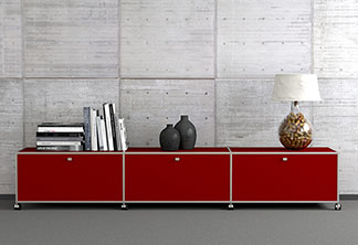 Lowboard als Hingucker: Ein rotes Lowboard auf dem zwei Vasen, Bücher und eine Lampe stehen, steht an einer Zimmerwand.