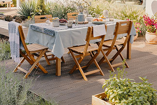Das richtige Set für den Garten: Eine große Terrasse auf der ein großer rechteckiger Gartentisch aus Holz mit fünf Holzstühlen steht.
