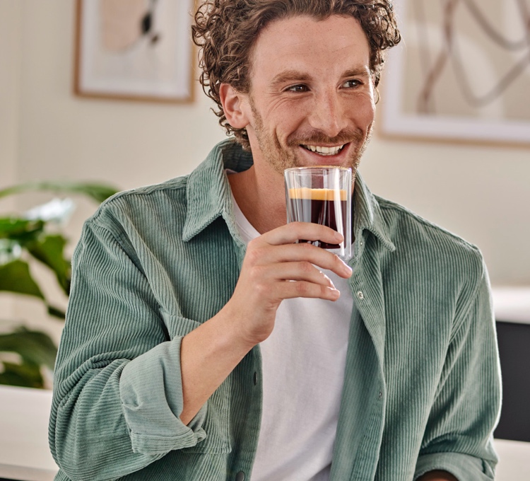 Mann hält ein Glas Caffè Crema in der Hand