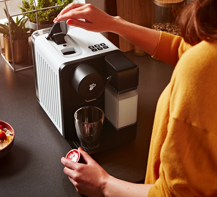 Eine Frau legt eine Kaffeekapsel in das Kapselfach der Cafissimo milk